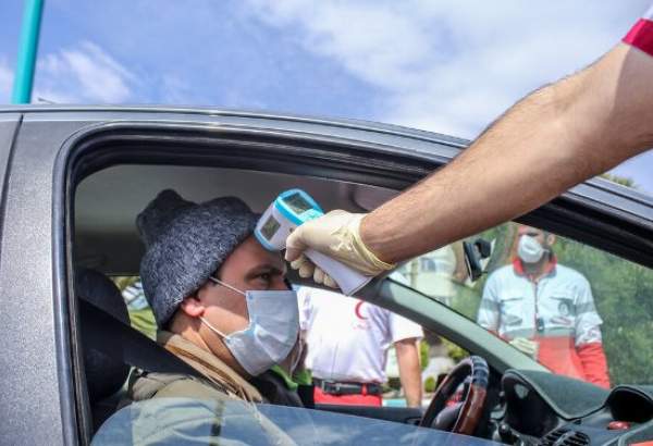 An Iranian Red Crescent volunteer monitors body temperature of people in Yazd, central Iran as part of measures to screen the public for symptoms of new coronavirus.