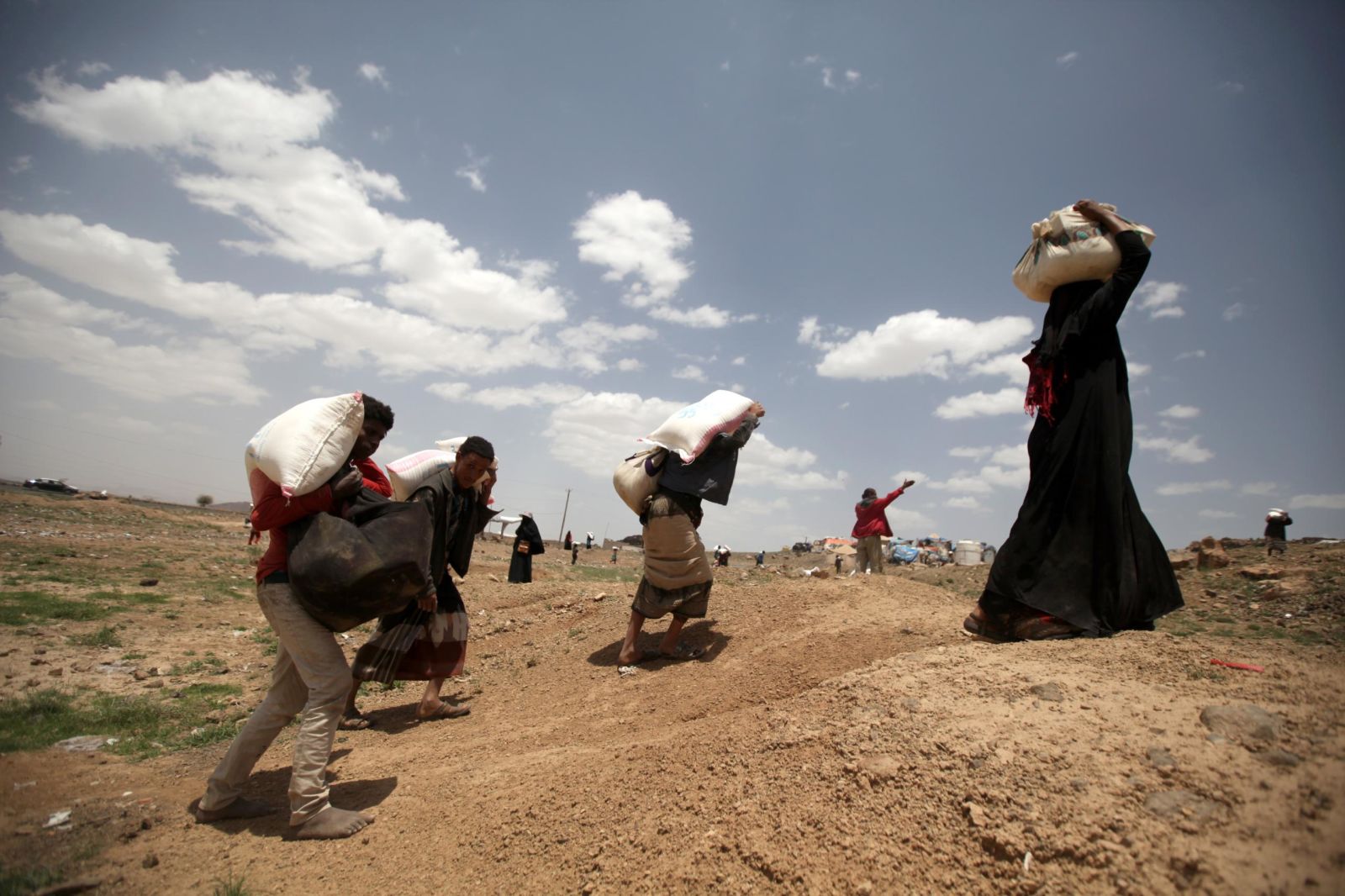 نیازمندان یمنی در حال حمل کمک‌های خیریه که همزمان با ماه مبارک رمضان دریافت کرده‌اند.