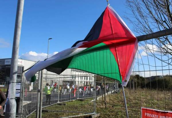 British activists hang a Palestinian flag on the fences as they stage a protest to insist for halting to Israel arms sales at headquarters of Elbit Systems, a weapons manufacturing company, in Bristol, United Kingdom on March 23, 2024 [Burak Bir – Anadolu Agency]