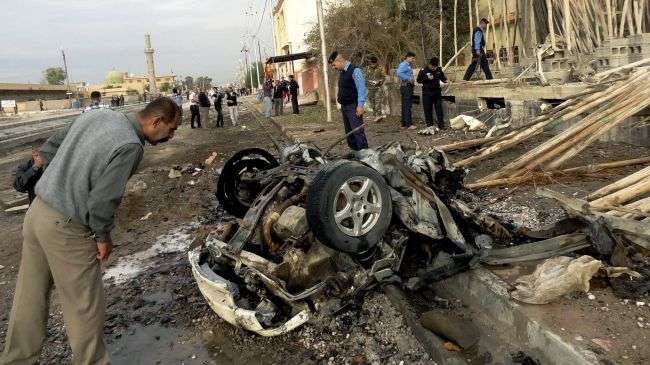 Iraqi civilians and policemen inspect the site of a car bomb attack in the northern city of Kirkuk on November 20, 2012.