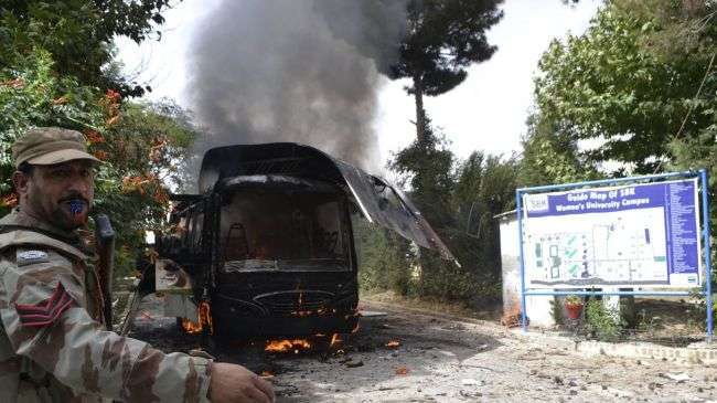 A Pakistani soldier stands near a burning bus at the site of a bomb blast in Quetta on June 15, 2013.