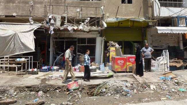 Iraqis inspect the damage outside shops in Baghdad on June 25, 2013 following an explosion the night before.