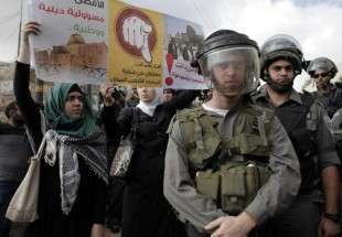 Israeli security forces stand in front of Palestinians holding up a placard during a rally near the entrance of Al-Aqsa mosque compound to protest after authorities restricted access to the esplanade on October 15, 2014 outside Jerusalem