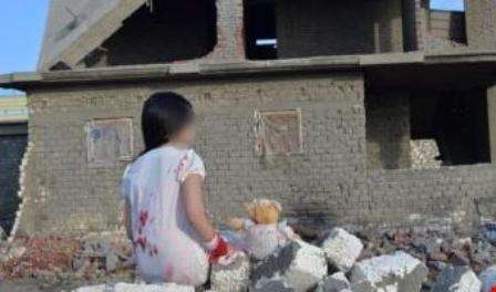 صورة مفبركة لمنزل مهدوم، حيث تجلس فتاة ملطخة بالدماء