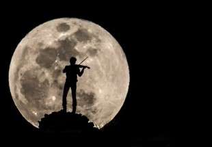 "كمنجاتي" يعزف وطائرة تطير على خلفية القمر العملاق