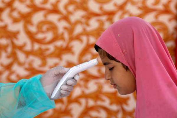 A health worker wearing a protective gear checks a girl