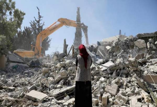 Palestinian woman watches on as Israeli forces raze down her home