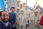 A group of Iranian in hospital gowns and protective gears against the new coronavirus pose for a photo.